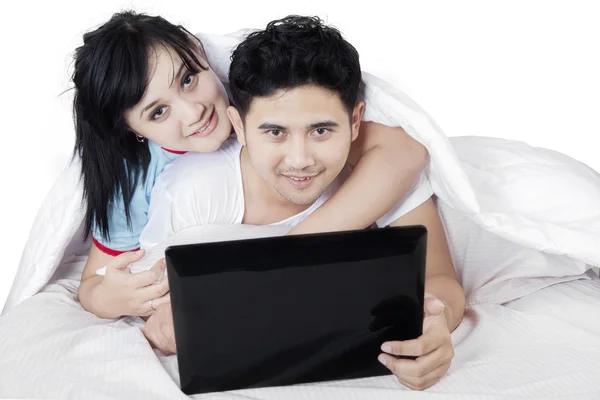 Couple with laptop cuddling on bed — Stock Photo, Image