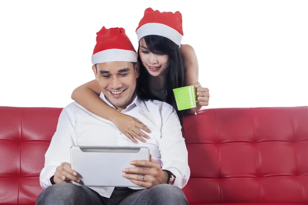 Couple dans les chapeaux de Noël en utilisant une tablette numérique — Photo