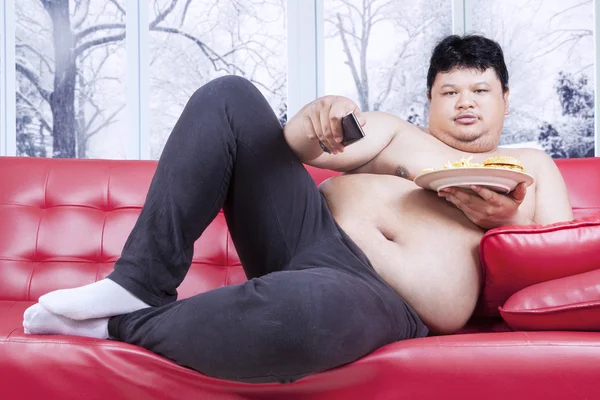 Fat man eats fast food and watching tv — Stock Photo, Image