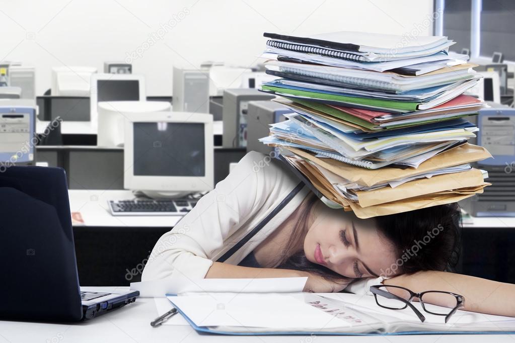 Tired female worker with paperwork on desk