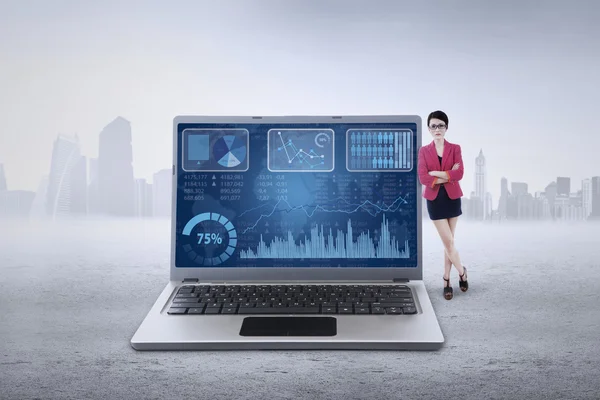 Kvinnlig arbetare lutar på laptop med diagram — Stockfoto