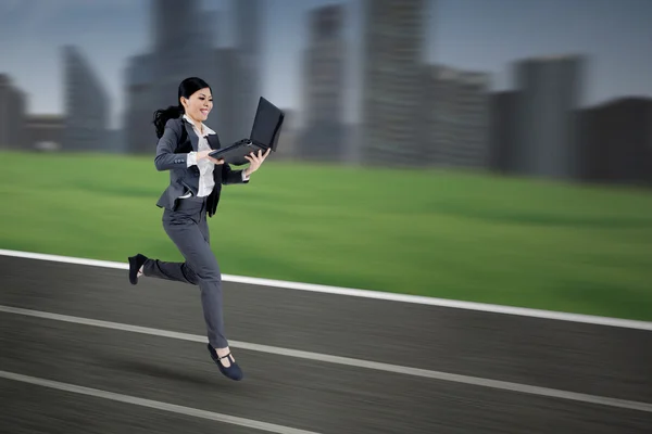 Бизнесменка с ноутбуком бежит по трассе — стоковое фото