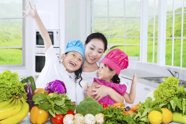 Dos niños y su madre cocinando verduras — Foto de Stock