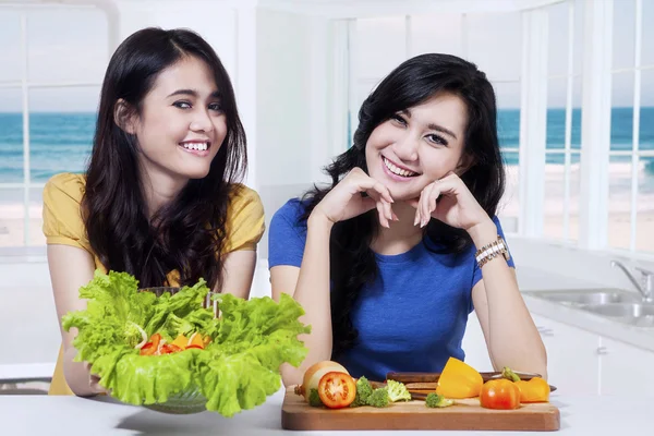 Due ragazze che mostrano insalata di verdure — Foto Stock