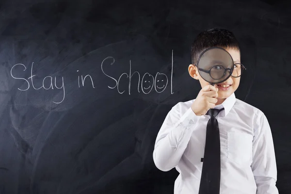 Ragazzo con lente di ingrandimento e testo Soggiorno a scuola — Foto Stock