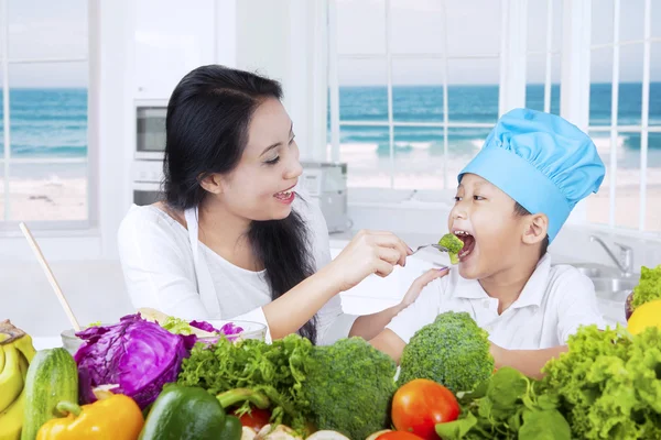 Mãe alimentando seu filho com legumes — Fotografia de Stock