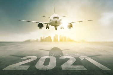 Havaalanı pistinde 2021 numara ve modern şehir arka planında uçak kalkışı. Güneş doğarken çekilmiş.