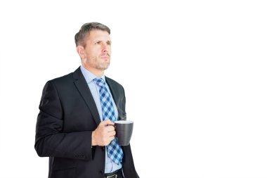 Kendine güvenen işadamı stüdyoda dalgın bir ifadeyle dikilirken elinde bir fincan kahve tutuyor. Beyaz arkaplanda izole