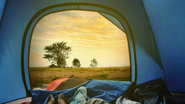 在森林里露营时 年轻女子的脚躺在帐篷里 日出时分可以看到黎明的天空 — 图库照片