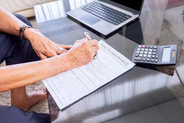 Закрыть Руки Пожилого Человека Заполняющего Медицинскую Страховку Рядом Ноутбуком Калькулятором — стоковое фото