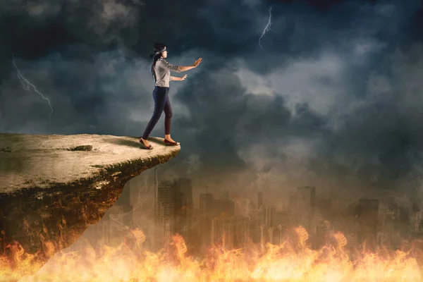 若い実業家が崖の上を歩いている嵐の空の背景に火の街で — ストック写真