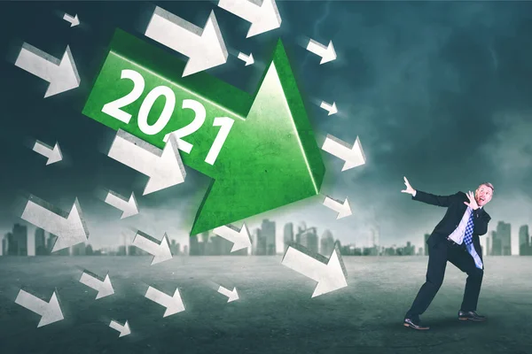 恐惧的商人站在乌云密布的天空中 被2021年数字的箭射中 — 图库照片