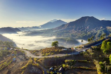 Wonderful aerial scenery of misty Pinggan village with mount Batur at morning time in Bali. Indonesia clipart