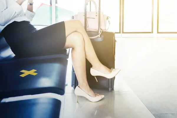 靠近坐在椅子上的年轻女商人的腿 上面有交叉标志 以便在机场休息室保持距离 — 图库照片