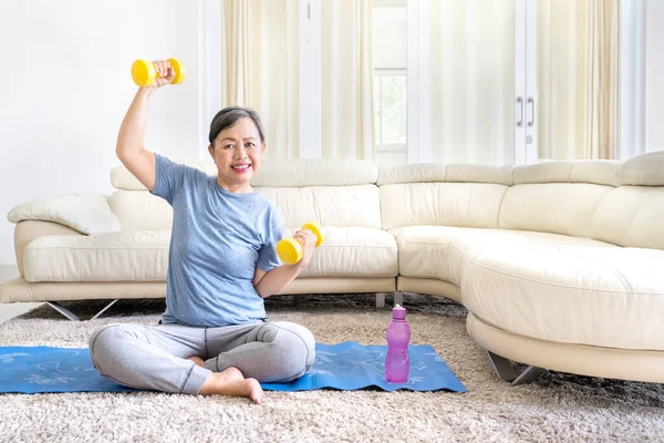 Äldre Kvinna Som Tränar Med Två Hantlar Sittande Madrassen Vardagsrummet — Stockfoto