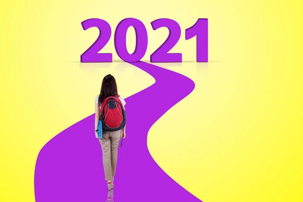 女生背负背包 走紫色道路走向2021年数字的背景图 — 图库照片