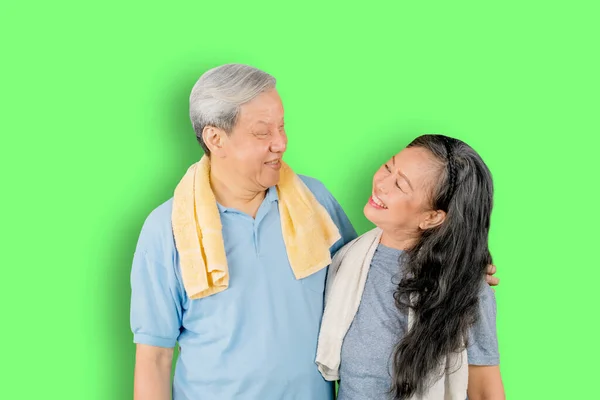 Szczęśliwa Para Starców Odzieży Sportowej Stojących Razem Studio Zielonym Tle — Zdjęcie stockowe