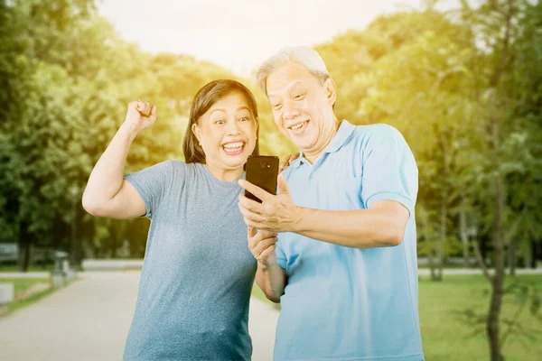 Feliz Pareja Ancianos Leyendo Buenas Noticias Teléfono Celular Mientras Están — Foto de Stock