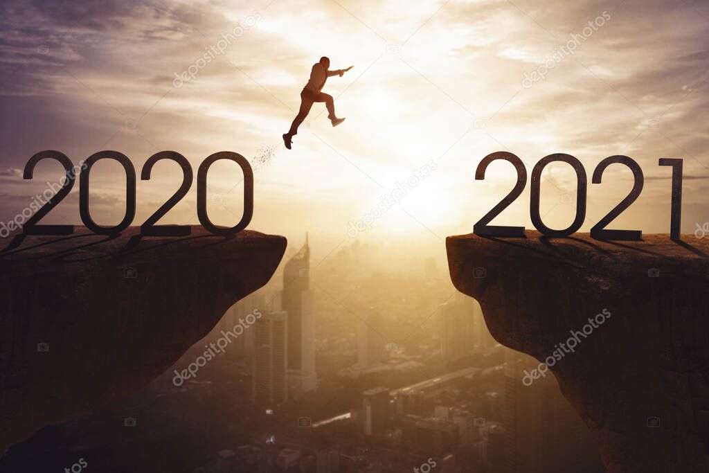 Young businessman jumping gap on the cliff with numbers 2018 and 2019 at sunrise time with cityscape background