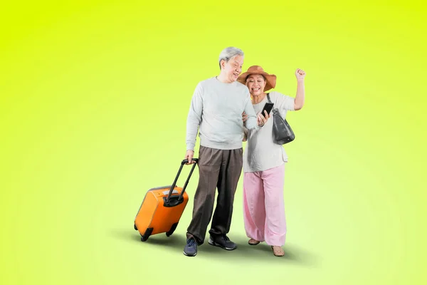 Old Couple Using Smartphone Happy Expression While Carrying Luggage Studio — Stok fotoğraf