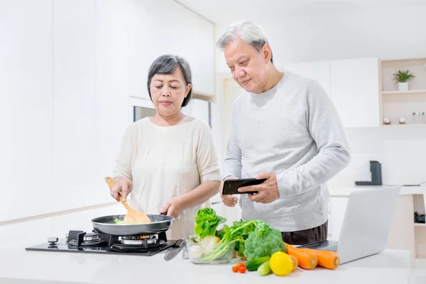 Seniorenpaar Kocht Gemeinsam Der Küche Während Rezepte Auf Dem Smartphone — Stockfoto