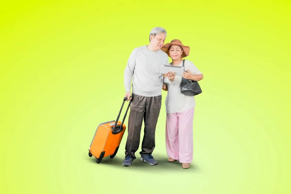 Senior Couple Using Digital Tablet While Carrying Luggage Vacation Standing — Stock Photo, Image