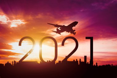 2021 'in üzerinde uçan uçak silueti ve gündoğumu arka planında gökyüzü olan şehir sayısı
