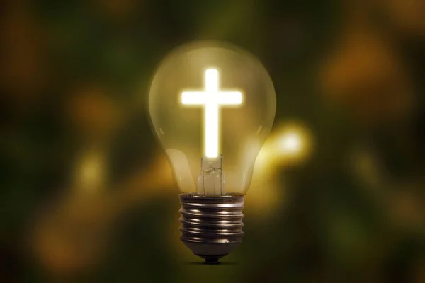 Close up of light bulb with shining cross symbol in blurred sparkling lights background