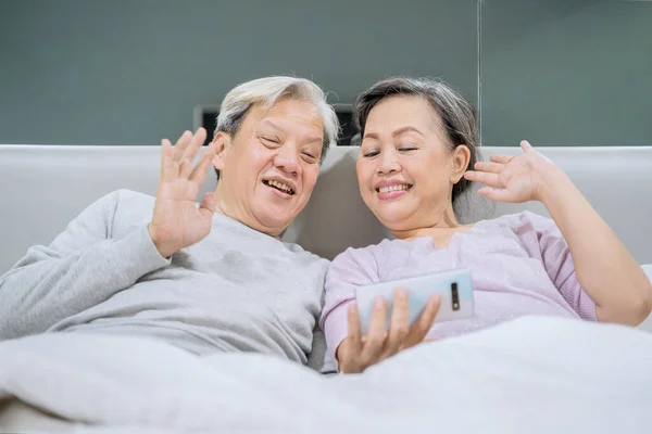 어르신 부부가 침대에 손자와 휴대폰으로 통화를 있습니다 가정에서 — 스톡 사진