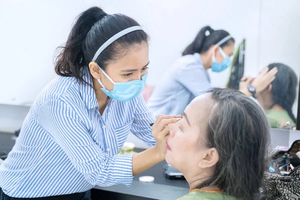 Bild Ung Kvinna Som Bär Ansiktsmask Medan Hon Applicerar Ögonskugga — Stockfoto