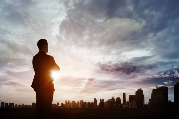 夜明けの空を背景に立ちながら 現代都市を日の出時に見て自信のあるビジネスマンの低角度ビュー — ストック写真