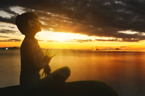 年轻女子在海滨做瑜伽运动的侧视图 她坐在日落时间的背景下 — 图库照片