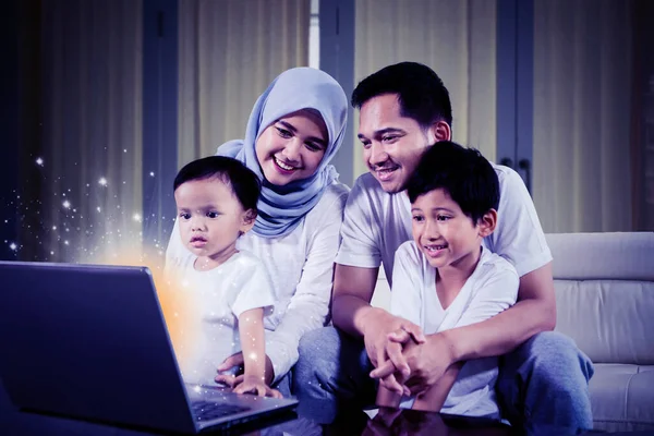 Keluarga Muslim Bahagia Menggunakan Laptop Dengan Monitor Berkilau Sambil Duduk — Stok Foto