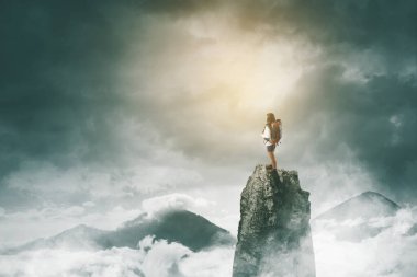 Sisli bir sabahta tepede dikilirken sırt çantası taşıyan kadın yürüyüşçünün arka görüntüsü.