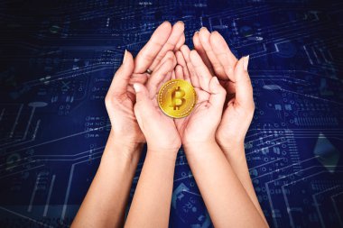 Anne ve küçük çocuğun elleri, devre kartı geçmişi olan bir bitcoin tutarken yakın plan.