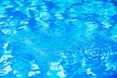 Mavi suyun yüzeyinde dalgalanmalar olan yüzme havuzunu kapatın.