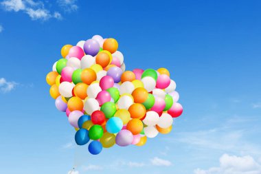 Mavi gökyüzünde uçarken kalp şeklindeki renkli balonları kapat.