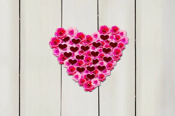 Top view of pink flowers with knick knacks shaped heart symbol on the wooden table. Valentines day concept