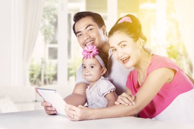 Mutlu ebeveynler evde karantina yaparken kızlarıyla birlikte dijital tablet kullanıyorlar.