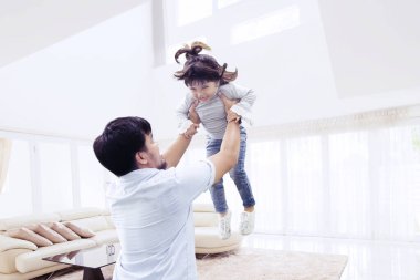 Mutlu bir babanın kızını kaldırırken birlikte oturma odasında eğlendiği bir resim. Evde vuruldu.