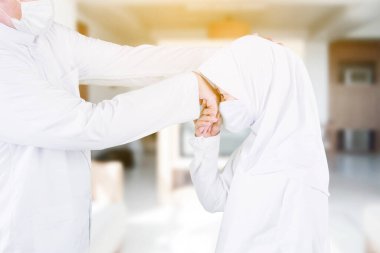 Mübarek bayramda evde babasından el sıkışırken ve özür dilerken yüz maskesi takan Müslüman küçük kız.