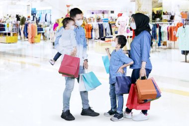 Coronavirus salgını sırasında alışveriş merkezinde alışveriş yaparken yüz maskesi takan Müslüman bir ailenin fotoğrafı