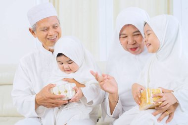 Mübarek bayramında oturma odasındaki kanepede otururken torunlarıyla konuşan mutlu Müslüman büyükanne ve büyükbaba. Evde vuruldu.
