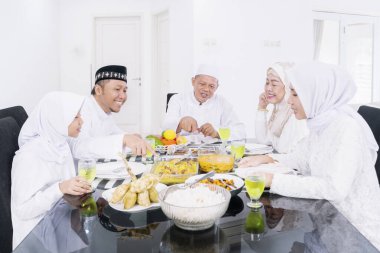 Mübarek bayramında evde yemek yiyen üç kuşak mutlu Müslüman aile.