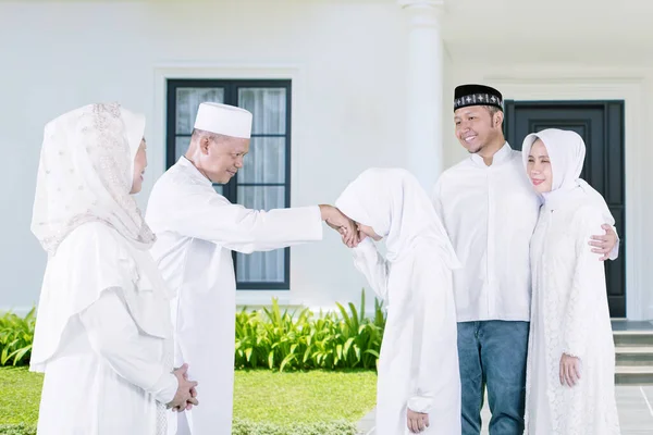 祝福の手のジェスチャーを示すイスラム教徒の女の子イード ムバラク彼の両親に家の前で両親と一緒に立っている間 — ストック写真