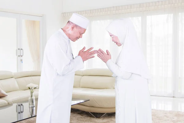 在开斋节期间 穆斯林老两口在家中客厅里手牵手 相互原谅的侧面景象 — 图库照片