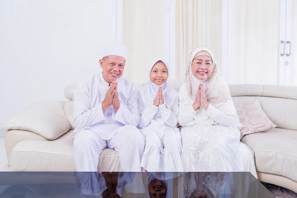 在家里客厅里 穆斯林小女孩和她的祖父母坐在沙发上 一边举手表决 一边向穆巴拉克致意 — 图库照片