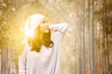 Sonbahar parkında güneşli arka planda duran genç bir bayanın tatili.