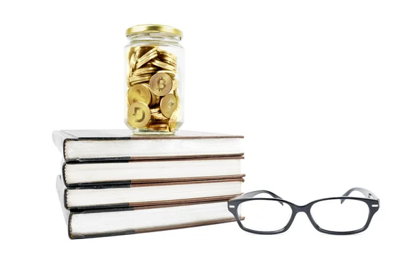 把装满加密货币硬币的玻璃瓶关上 里面堆满了书本和眼镜 因白人背景而被隔离 — 图库照片
