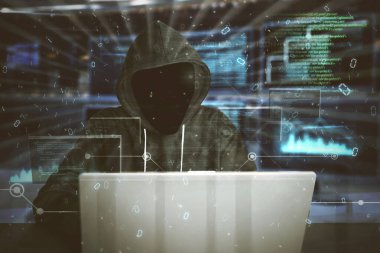 Hooded hacker typing program code on a laptop while hacking security system in the cyberspace